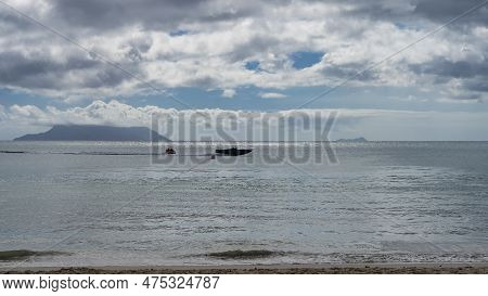 A Motor Boat With A Tourist Trailer Is Rushing In The Calm Ocean. Silhouettes Of Islands On The Hori