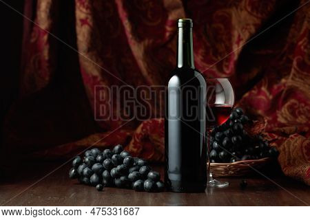 Still Life With Red Wine And Blue Grapes On An Old Wooden Table.
