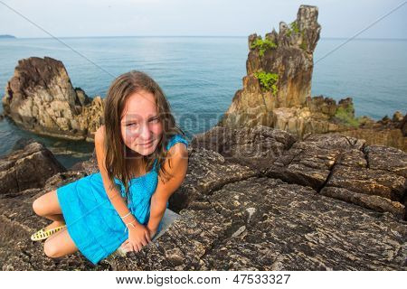 Teengirl in un abito blu nelle rocce della costa.