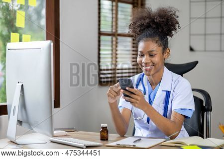 An American Female Doctor Is Using A Mobile Phone, She Is A General Practitioner And Internal Medici