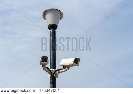 Surveillance Cameras Mounted On A Lamp Post Against A Blue Sky. Security Cctv Camera. Security In Th