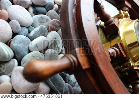 Part Of Sailboat Helm With Сopper Edging Compass Inside On A Round Sea Rocks Background