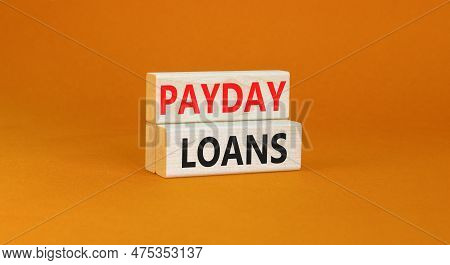 Payday Loans Symbol. Concept Words Payday Loans On Beautiful Wooden Block. Beautiful Orange Table Or