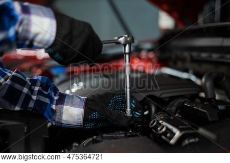 Female Auto Mechanic Unscrewing A Nut To Replace A Car Spark Plug.