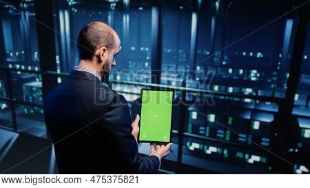 Data Center Technician Holding Tablet With Green Screen In Server Room, Looking At Isolated Chroma K