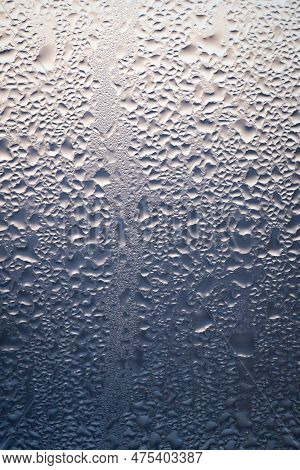 Backlit Chaotic Water Drops On Lightbeige And Blue Glass Background. Condensation After Rain Or Show