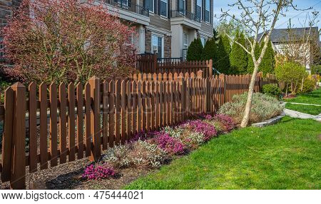 Nice New Wooden Fence Around House. Wooden Brown Fence With Green Lawn And Nicely Landscaped Front Y