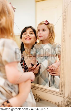 A Cute Little Girl In A Plaid Dress And Mom Looks In The Mirror And Primping.
