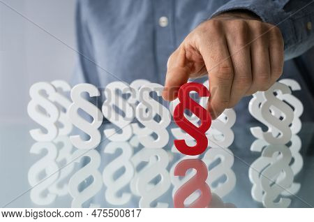 Close-up Of Businessman's Hand Holding Red Paragraph Sign With White Paragraph Signs In Background