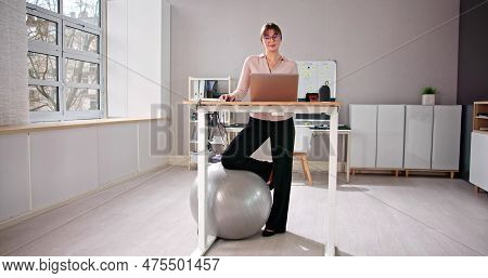 Woman Using Adjustable Height Standing Desk In Office For Good Posture