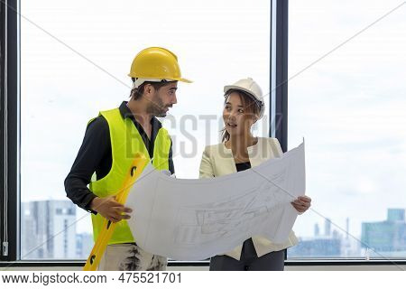 Team Engineers With Draft Plan Of Building On Constructing Site.