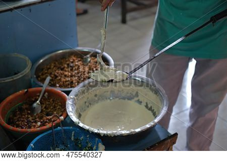 A Man Pouring Wet Flour Into A Spatula To Be Fried To Make Indonesian Vegetable Fritter Or Ote-ote O