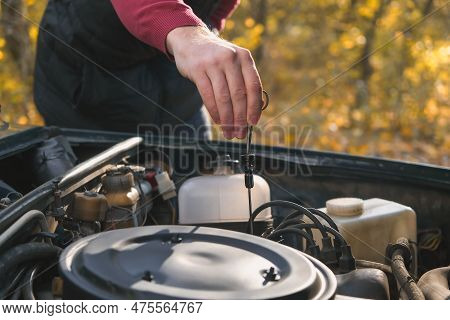 A Man Checks The Oil Level In The Car Engine. Self-service Of The Car. Periodic Check Of The Oil Lev