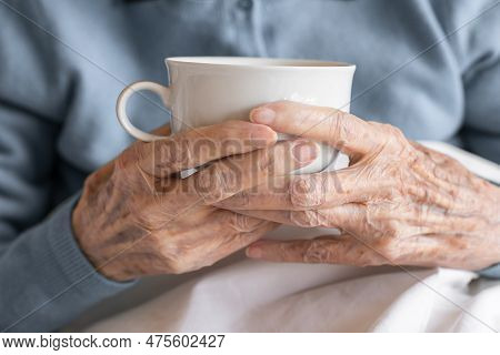 Hands Of An Elderly Women Holding A Cup, Close Up, On A Bed In A Hospital. Concept Of Aging Process
