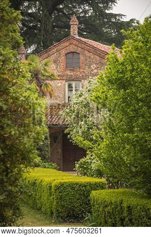 Stone Brick Country House With Terracotta Tiles Surrounded By An Italian-style Garden With Trees And