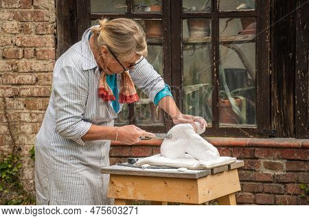 Sebastiano Da Po, Italy - April 12 2023: Woman Carving A Stone During An Outdoor Sculpture Lesson Or