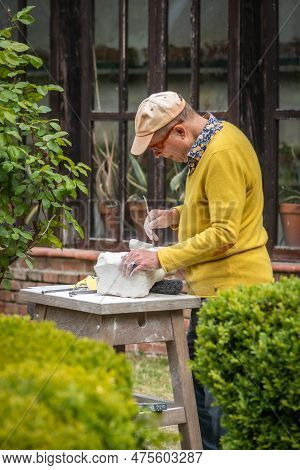 Sebastiano Da Po, Italy - April 12 2023: Man Carving A Stone During An Outdoor Sculpture Lesson Or C