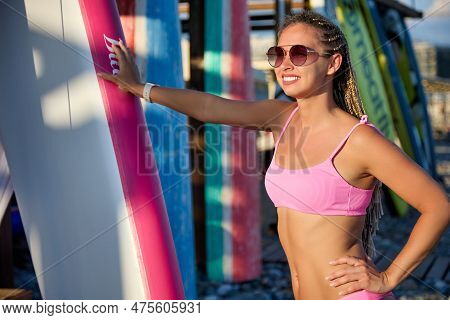 Tanned Girl With A Smile On Her Face Stands At The Swimming Board, Holding On To The Sap With Her Ha