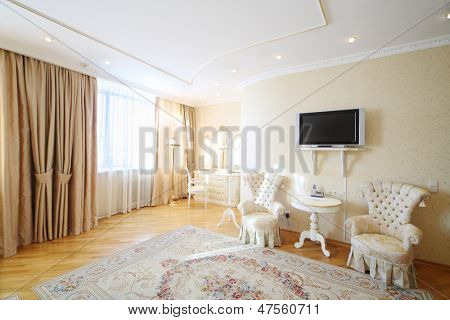Chambre luxueuse avec beaux fauteuils, miroir mural et TV dans le style classique.