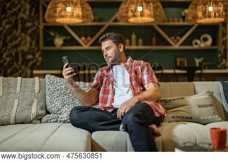 Portrait Of A Cheerful Man With Smart Phone At Home. Guy Using Phone At Home. Middle Eastern Mature 