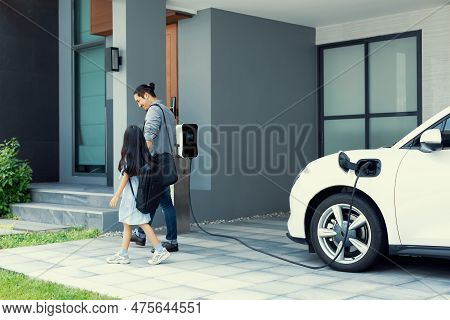 Progressive Father And Daughter Plugs Ev Charger From Home Charging Station To Electric Vehicle. Fut
