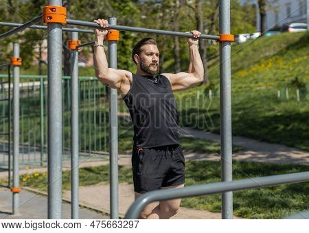 Athletic Lebanese Man In Sportswear Doing Pull-ups Exercises On Horizontal Bar. Young Guy Pumping Up