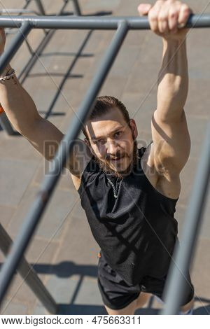 Athletic Lebanese Man In Sportswear Doing Pull-ups Exercises On Horizontal Bar. Young Guy Pumping Up