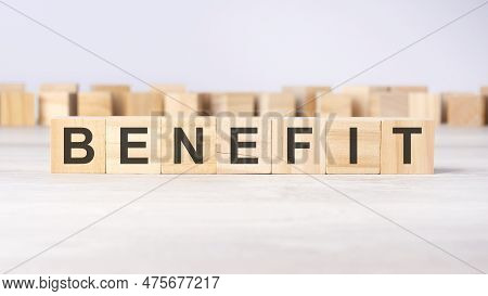 Word Benefit Inscribed On Wooden Cubes Lying On A Light Table. Economy And Investments Concept.