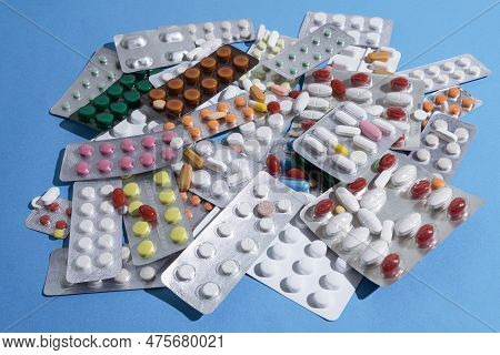 A Large Pile Of Pills In Bundles Scattered On The Table. A Mound Of Multi-colored Tablets And Bliste