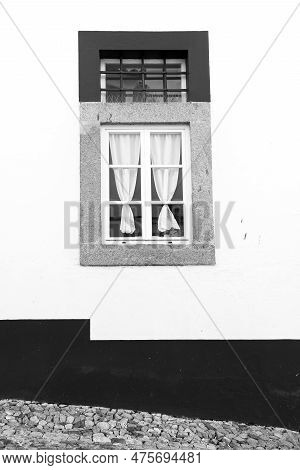 Typical Portuguese Facade With White Wooden Window And Curtain On Whitewashed Facade In Evora Town