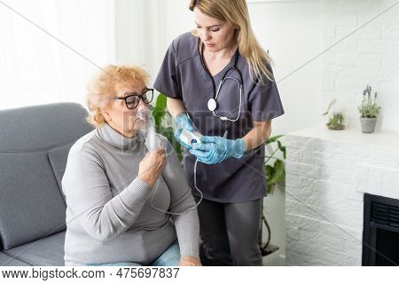 Elderly Woman Using Inhaler For Asthma And Respiratory Diseases At Home