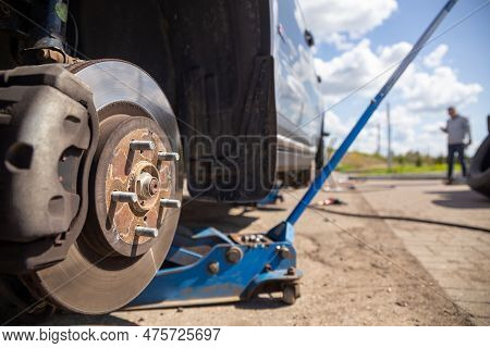Car On Tire Mounting With Removed Wheel On Pneumatic Jack, Seasonal Tire Change, Car Service Concept