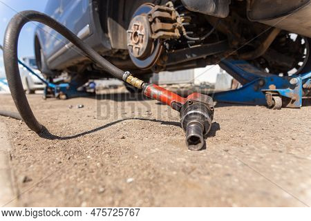 Pneumatic Wrench Tool On The Asphalt And A Car Jack For Lift Up The Body And Changing The Tire. Car