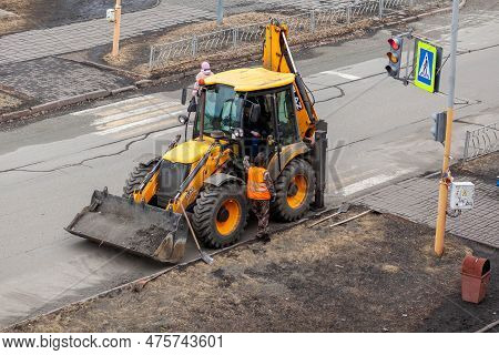 26.04.2023, Kemerovo, Russia. A Yellow Tractor Is Standing Or Driving On The Road Doing Road Work. S