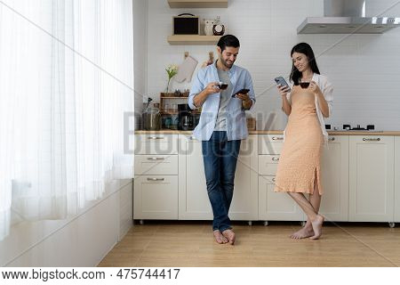 Handsome Bearded Young Man And Beautiful Young Woman Standing In Kitchen Drinking Morning Coffee Usi