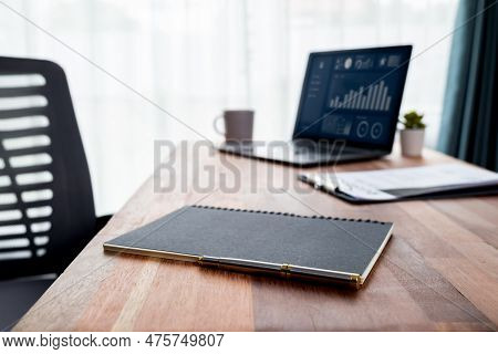 Wooden Desk In Office With Laptop Displaying Fintech Dashboard Business Data. Business Intelligence 