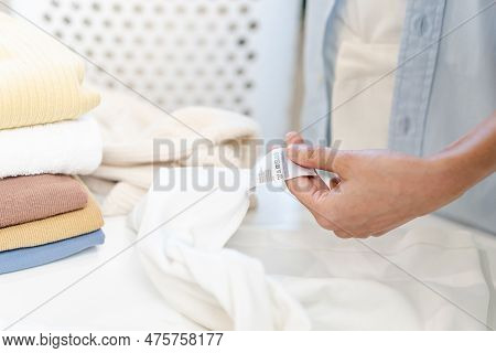 Housewife, Asian Young Woman Hand In Holding Shirt Label, Tag With Instructions, Guide Before Clean 