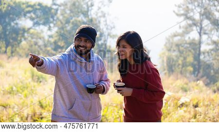 Couple Drink Coffee In Morning Time. Young Couple Holding Mugs While Enjoying The View Of Nature. \r