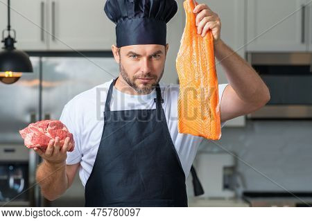 Professional Kitchen. Chef With Raw Meat Beef And Fish Salmon Fillet. Man In Uniform On Kitchen. Han