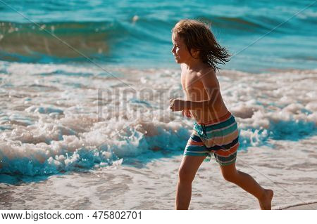 Child Running Through Water Close To Shore Along The Sea Beach. A Boy Runs Along The Sea Coast. Rest