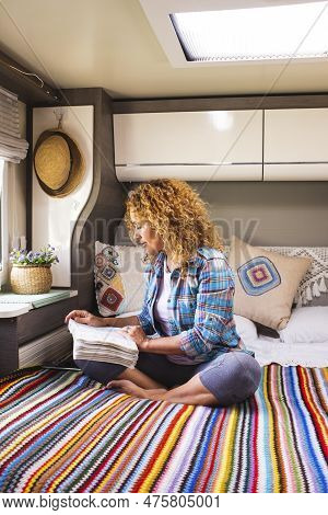 Vanlife And Relax. Serene Woman Reading A Book Sitting On Bed Inside Camper Van Bedroom. Relaxation 