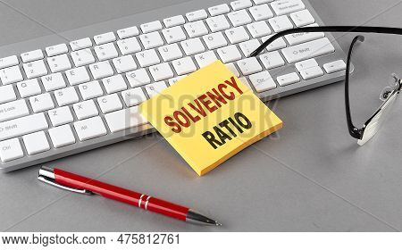 Solvency Ratio Text On Sticky With Keyboard, Pen Glasses On Grey Background