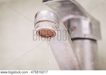 Water Dripping From Old Tap. Dirty Faucet In Bathroom, Warm Toned Photo