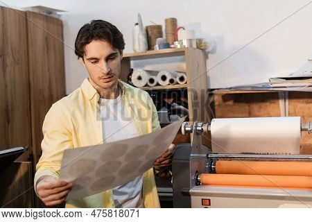 Typographer Looking At Printed Paper Near Professional Print Plotter.