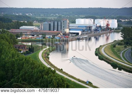 A Drone Perspective View Of A River Channel Near A Plant Or Factory. A Motor Boat Floats On The Wate