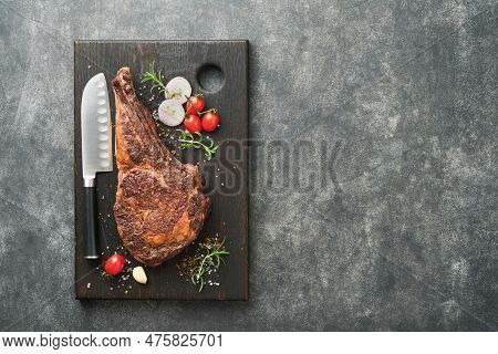 Tomahawk Steak. Sliced Grilled Tomahawk Beef Steak With Baked Cherry Tomatoes, Herbs And Salt On Old