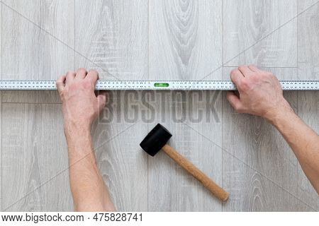 Man Checks The Evenness Of A Laminate Floor With A Level. Repair And Decoration Of Premises. Modern 