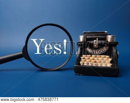 Magnifying Glass And Vintage Typewritter With The Word Yes On Blue Background