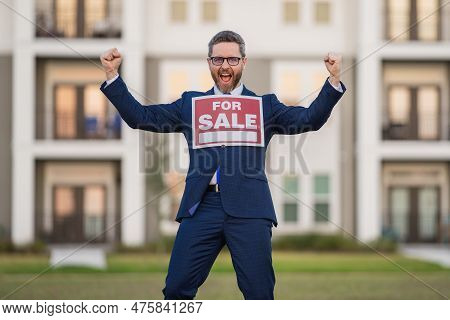 Handsome Real Estate Agent Holding Banner House For Sale. House With Land And Insurance. Man Real Es