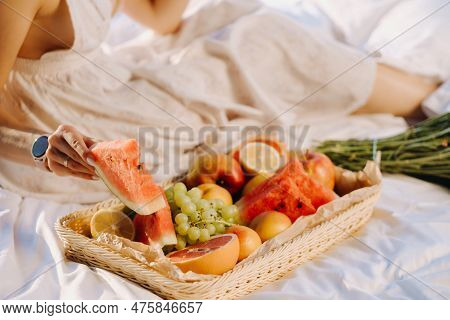 Close-up Of Assorted Fruits On A Tray. The Girl Takes The Fruit In Her Hands